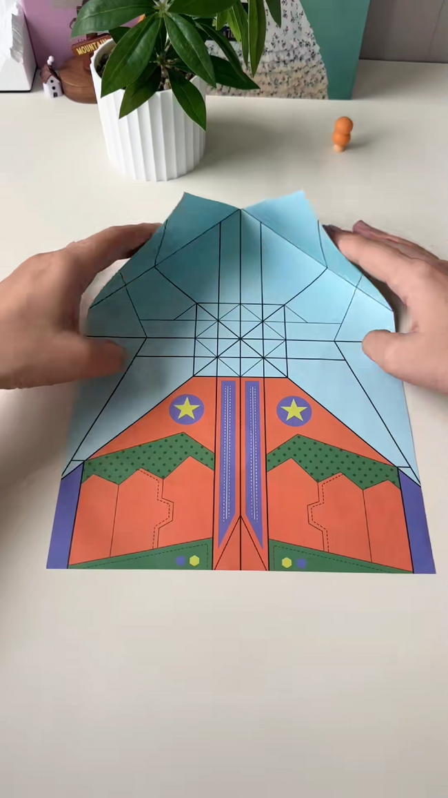 Real close-up of hands forming a wide-wing paper airplane