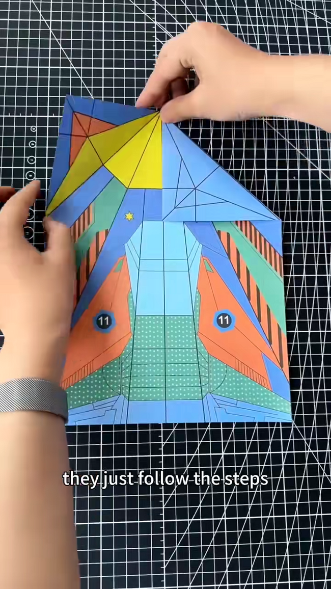 Real close-up of hands folding the printed Skybreaker paper plane